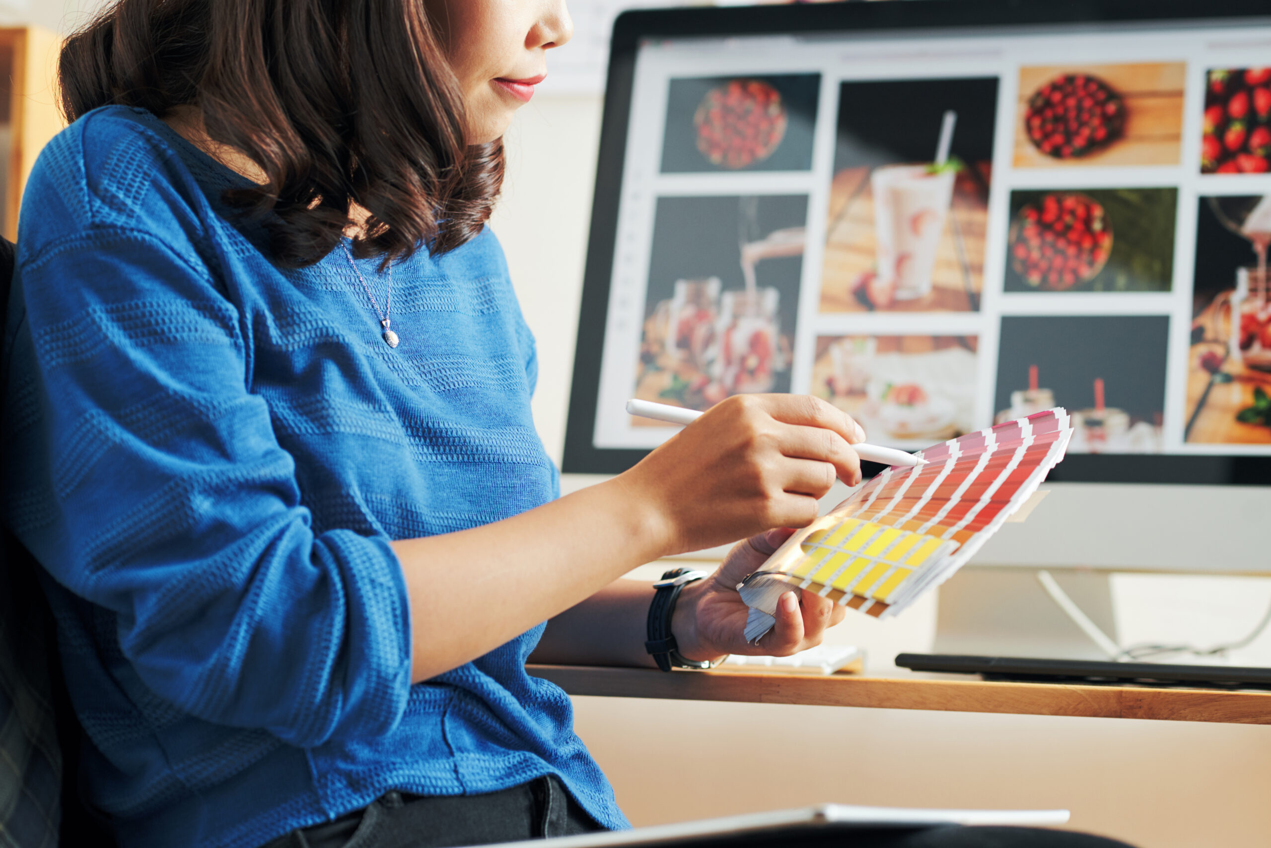 Close-up of Asian woman in blue sweater picking out palette for website design in modern office